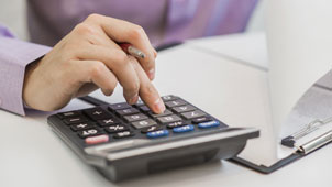 Hand with pen on pocket calculator